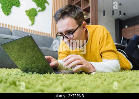 relaxed young man using a laptop on the floor at home. Stock Photo