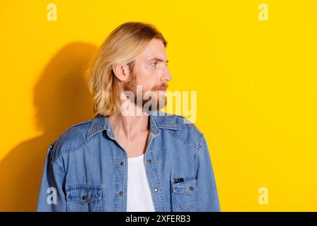 Photo portrait of pretty young guy look empty space wear trendy jeans outfit isolated on yellow color background Stock Photo