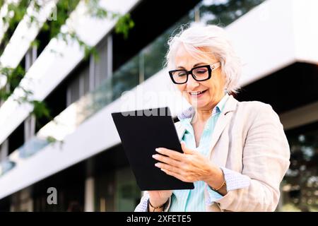 mature woman smiling while using digital tablet Stock Photo