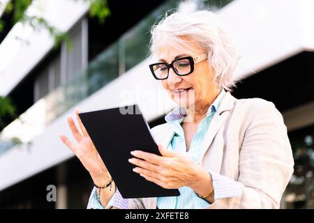 mature woman smiling while using digital tablet Stock Photo