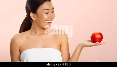 Young Woman Holding Red Apple in White Tank Top Stock Photo