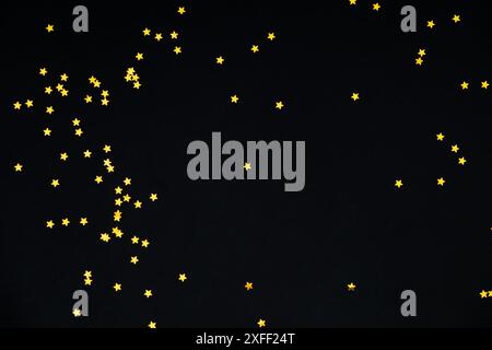 Golden glitter stars confetti on black background. Festive holiday pastel backdrop. Minimal concept. Luxury flat lay composition. Stock Photo