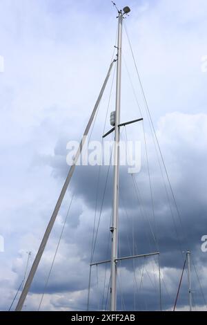 Lymington Harbour, England. 18 June 2024. A cloudscape viewed through the mast and rigging of a sailing boat. Stock Photo