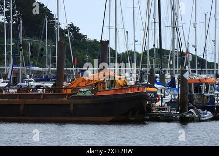 Lymington Harbour, England. 18 June 2024. An orange Berthon crane working alongside a boat in the harbour. Stock Photo