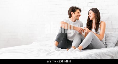 Young Couple Sitting On Bed Looking At Each Other Stock Photo