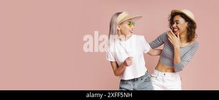 Two Women Laughing Together In Front Of A Pink Background Stock Photo