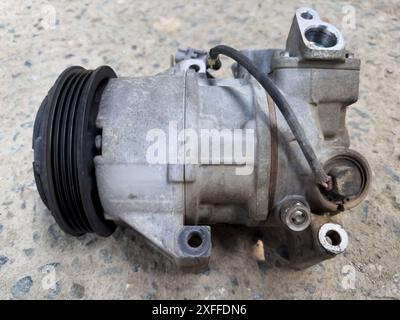 Automotive Air Conditioning Compressor on Ground Closeup View Stock Photo