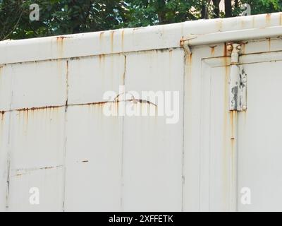 Corroded metal background. The metal wall is painted white with rust spots. Rusted metal background with rust marks, rust stains. Rystycorrosion. Stock Photo