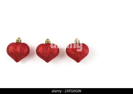 Three red heart shaped Christmas bulbs on a white background. View from above. Copy space Stock Photo