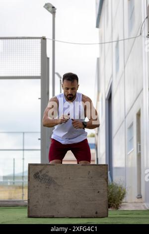 Man doing CrossFit jumping onto a box outdoors. Stock Photo