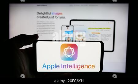 Person holding cellphone with logo of AI platform Apple Intelligence in front of business webpage. Focus on phone display. Stock Photo
