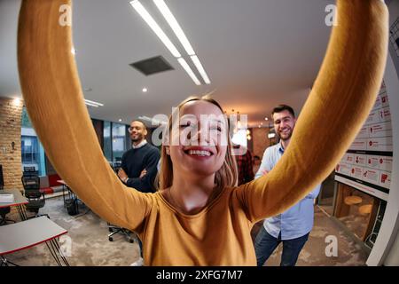 Wide-Angle Selfie of Business Blonde with Colleagues in Office Stock Photo