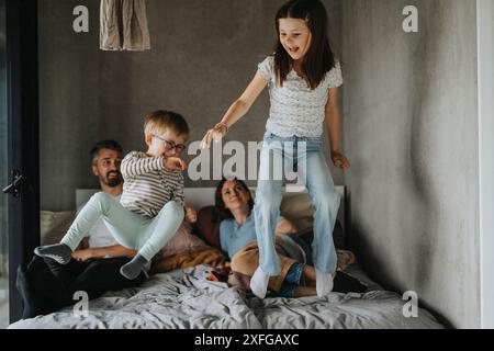 Brother and sister jumping on bed in bedroom Stock Photo