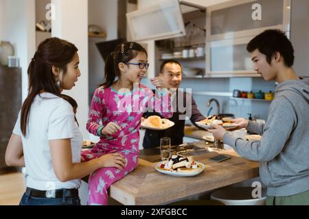 Family enjoying eating pancakes in kitchen at home Stock Photo