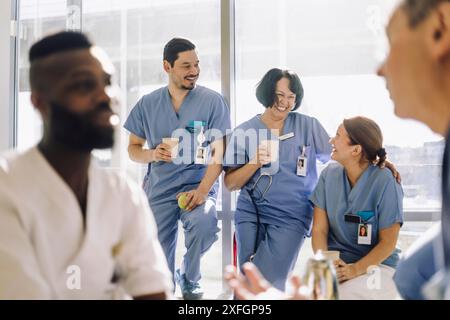 Happy male and female healthcare workers enjoying coffee during break at hospital Stock Photo