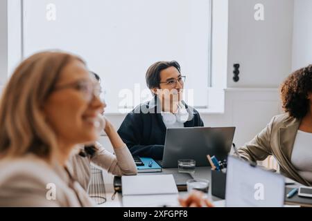 Businessman with wireless headphones sitting with colleagues in meeting room at office Stock Photo