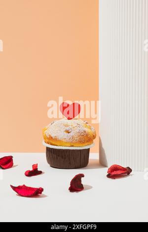 Cupcake with red heart and petals on bright background. Celebrate Valentine's Day. Stock Photo