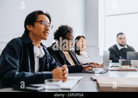 Mature businesswoman working on laptop while sitting with coworkers in office Stock Photo