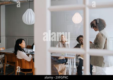 Female entrepreneur discussing ideas with coworkers in meeting room at office Stock Photo