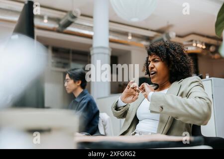 Tired businesswoman yawning while sitting in office Stock Photo