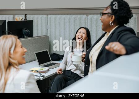 Female business professionals having fun and discussing in office Stock Photo