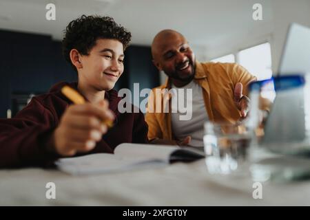 Happy father helping son doing homework at home Stock Photo