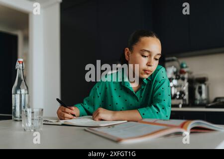 Focused girl reading while doing homework at home Stock Photo