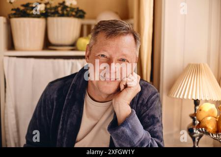 Portrait of smiling mature man leaning on elbow at home Stock Photo