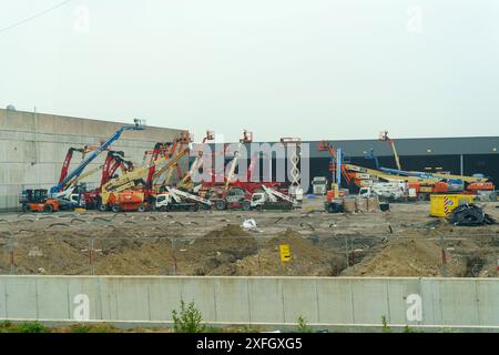 Kortrijk, Belgium - May 22, 2023: Various construction equipment parked in front of a building, ready for work. Machines include cranes, bulldozers, e Stock Photo