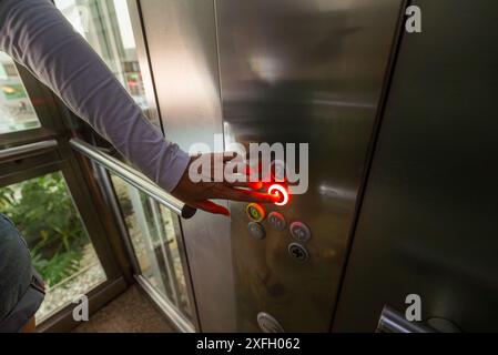 Woman pressing button inside elevator. Stock Photo