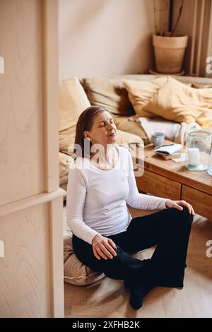 Elderly woman practicing yoga while sitting at home Stock Photo
