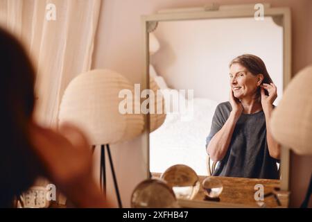 Smiling senior woman looking at reflection in mirror at home Stock Photo