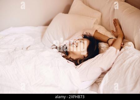 Smiling young woman lying down on bed at home Stock Photo