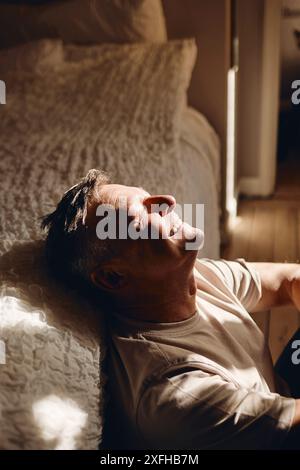 Happy man sitting near bed at home Stock Photo
