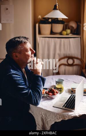 Side view of mature man sitting with hands clasped at home Stock Photo