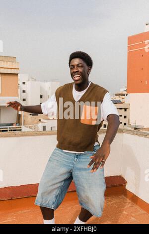 Happy young man in casuals dancing on rooftop Stock Photo