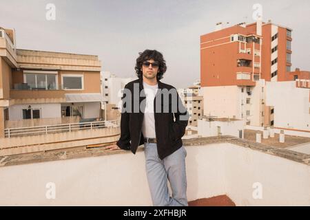 Fashionable young man posing near wall on rooftop Stock Photo