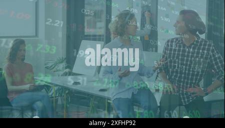 Image of graphs and trading board, diverse coworkers sitting on desk and discussing in office Stock Photo