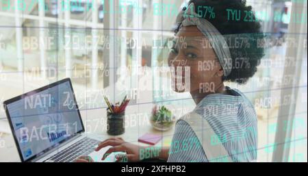 Image of trading board over biracial woman analyzing infographic interface on laptop Stock Photo