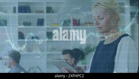 Image of multiple graphs with changing numbers, caucasian woman using digital tablet in office Stock Photo