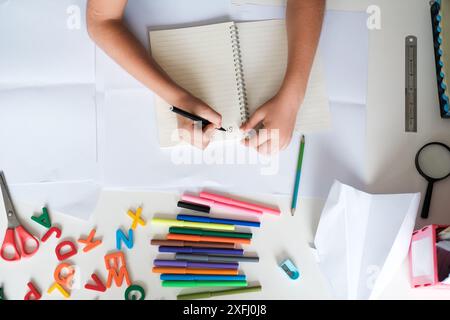 Top view of a child work desk and hands boy from a preparatory school. Homework. Stock Photo