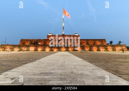 Wonderful view of a square and the flag of Vietnam (red flag with a gold star) fluttering over a tower of the Citadel on blue sky background in Hue. Stock Photo