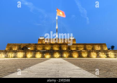 Wonderful view of a square and the flag of Vietnam (red flag with a gold star) fluttering over a tower of the Citadel on blue sky background in Hue. Stock Photo