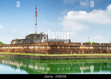 Wonderful view of a square and the flag of Vietnam (red flag with a gold star) fluttering over a tower of the Citadel on blue sky background in Hue. Stock Photo