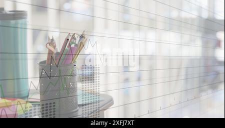Image of multiple graphs with changing numbers over over keyboard and pencils in office Stock Photo