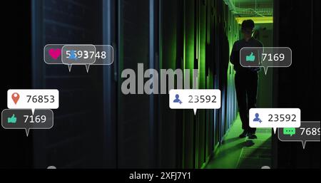 Animaton of social media icons against asian male engineer using laptop at computer server room Stock Photo
