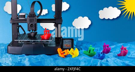 Colorful model printed boats droping into paper ocean after production. abstract and creative 3d printing farm  line concept background. Stock Photo