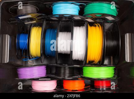 black box  filled with colorful  3d printing filament spool like PLA PETG and ABS. Modern technology and material DIY background Stock Photo