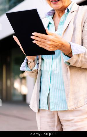 mature woman smiling while using digital tablet Stock Photo
