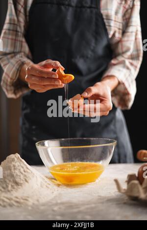 Woman separating egg yolk and egg white over transparent bowl in kitchen while cooking at home. Cooking protein dish, pastry, pastry with eggs. Fresh Stock Photo